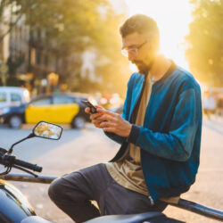 バイクの近くでスマートフォンを操作する男性